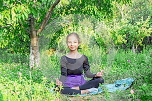 Pretty girl doing yoga exercises, little girl doing yoga exercises in the garden