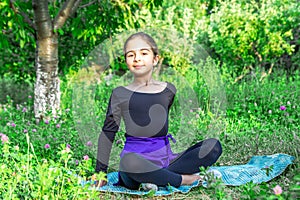 Pretty girl doing yoga exercises, little girl doing yoga exercises in the garden