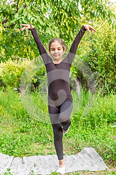 Pretty girl doing yoga exercises, little girl doing yoga exercises in the garden