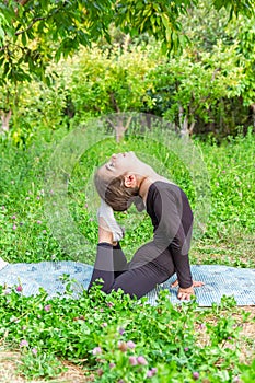 Pretty girl doing yoga exercises, little girl doing yoga exercises in the garden