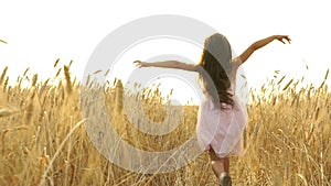 Pretty girl in the dress is running across the field.