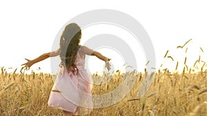 Pretty girl in the dress is running across the field.