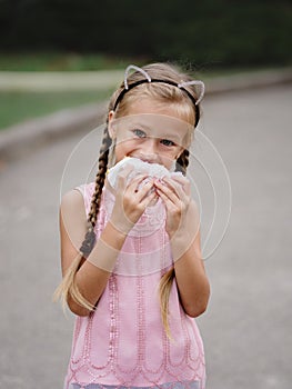 A pretty girl is eating a cheeseburger on a blurred street background. A little girl with a sandwich.