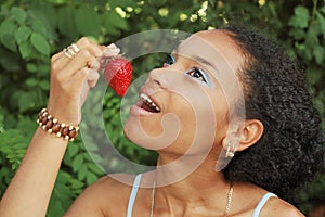 Pretty girl eating a strawberry