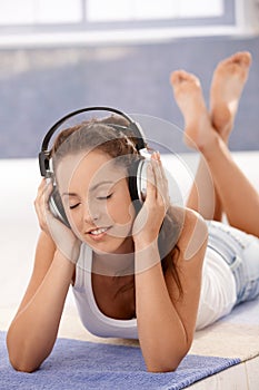 Pretty girl enjoying music laying on floor