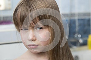 Pretty girl face portrait, child with beautiful eyes and long wet fair hair on blurred background of bathroom