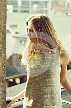 Pretty girl in fashionable grey dress on balcony