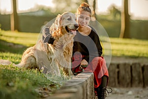 Pretty girl with golden retriever dog at nature