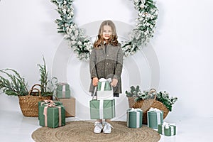 Pretty girl in green dress holding present gift box near decorated Christmas tree