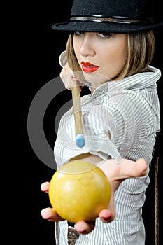 Pretty girl in hat with billiard cue and a ball