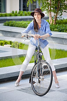Pretty girl in hat riding a bicycle at street