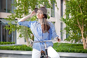 Pretty girl in hat riding a bicycle at street