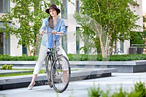 Pretty girl in hat riding a bicycle at street