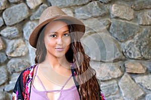 Pretty girl in hat by a rock wall