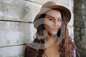 Pretty girl in hat by a wood wall