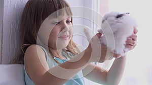 Pretty girl having fun, hugging and playing with decorative rabbit