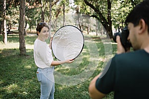 Pretty girl having a photo session while holding reflector