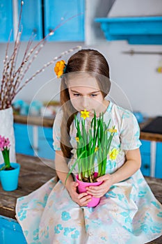 Pretty girl holding a pot of daffodil flowers in anticipation of spring and Easter