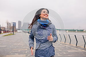 Pretty girl jogging on the river bank. Cloudy rain day