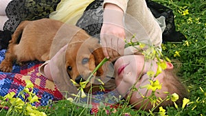 Pretty girl laying on green grass with a puppy