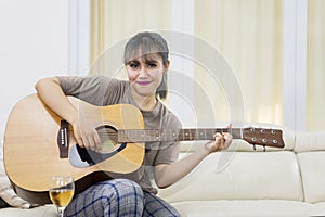 Pretty girl learning to play an acoustic guitar