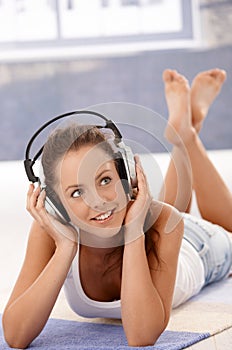 Pretty girl listening music laying on floor