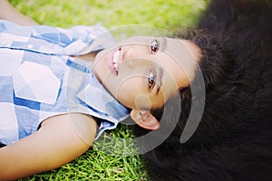 Pretty girl with long brunette hair lying on green grass