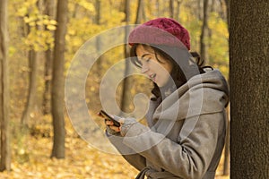 Pretty girl looking at her smartphone in the woods