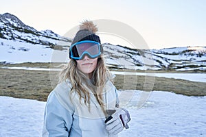 Pretty girl looks at the camera with a casual and calm appearance equipped with a hat and snow goggles