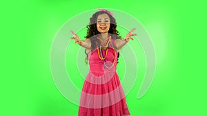 Pretty girl looks into the camera and then pulls her hands in front and having fun. Green screen