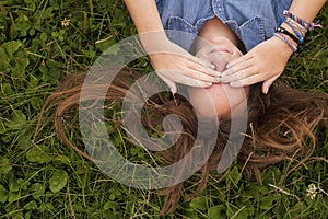 Pretty girl lying on the grass closes his eyes with his hands. Problems of adolescents