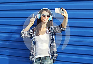 Pretty girl makes self-portrait on smartphone and listens to music in headphones