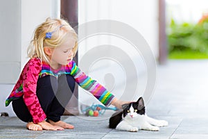 Pretty girl patting a cat outside