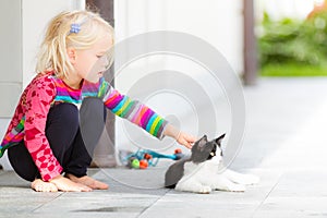 Pretty girl patting a cat outside