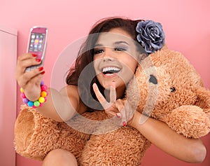 Pretty girl photographing herself and toy bear