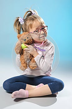 Pretty girl plays in the doctor treats a teddy bear on a gray ba