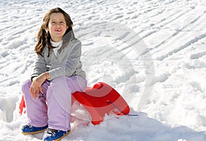 Pretty girl plays with the Red sled on the snow in the winter