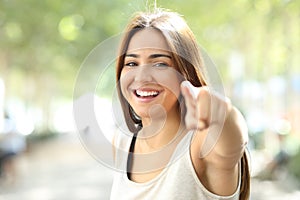 Pretty girl pointing at camera outdoors