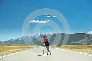 Pretty girl posing with long board on straight road