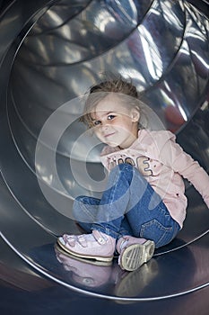 Pretty girl posing on a slide in the playground photo