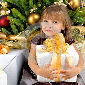 Pretty girl with present near the Cristmas tree