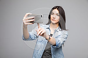 Pretty girl presses a finger on a touchscreen phone on gray background