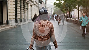 Pretty girl rear view enjoying spring outdoors. City lifestyle. Stylish hipster woman tourist walking on old town street