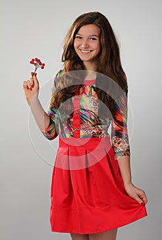 A pretty girl in a red dress with beautiful long brown hair. Photo in full growth.