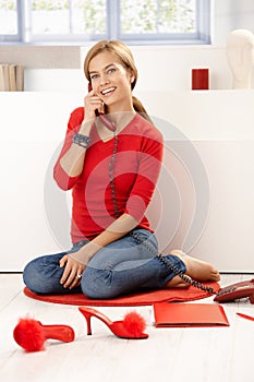 Pretty girl in red talking on phone at home