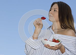 Pretty girl relaxing on balcony and eat red fresh