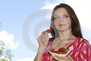 Pretty girl relaxing on balcony and eat red fresh