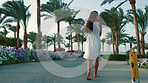 Pretty girl relaxing in palm trees park. Young woman walking at garden.