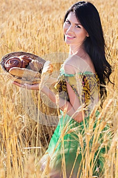 Pretty girl in rye field with basket of bread