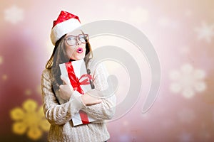 Pretty girl in Santa hat surprised holding giftbox